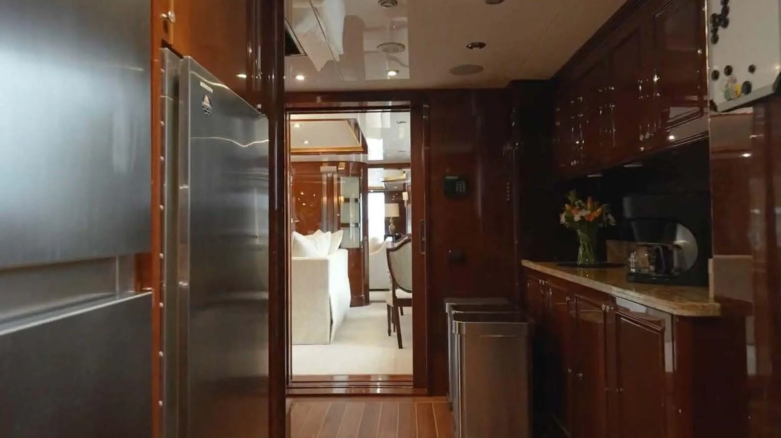 The yacht's galley features sleek cabinetry, modern appliances, and a view into the dining area. aboard DOMANI Yacht for Sale