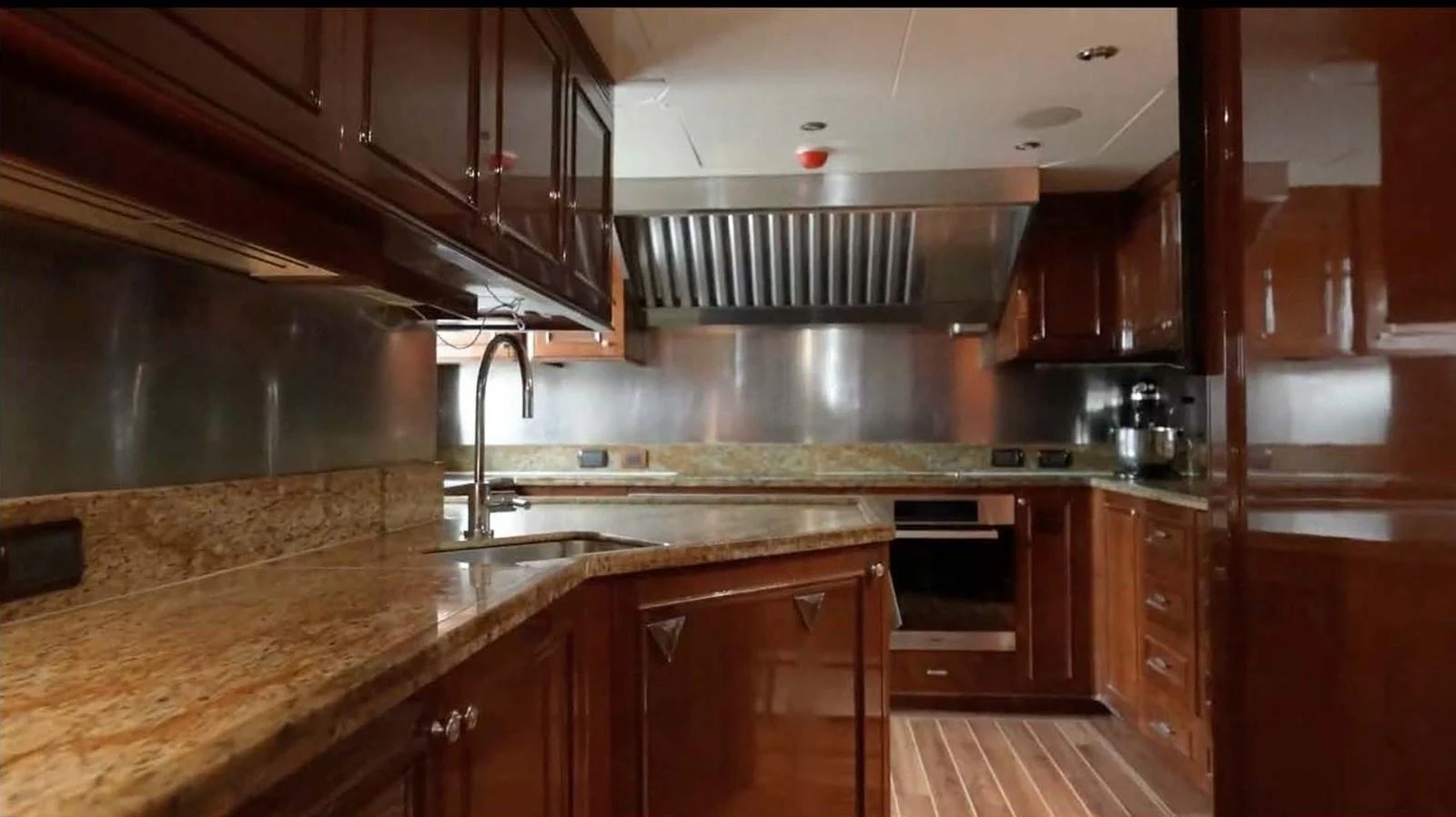 The galley features rich wood cabinetry, stainless steel appliances, and granite countertops. aboard DOMANI Yacht for Sale