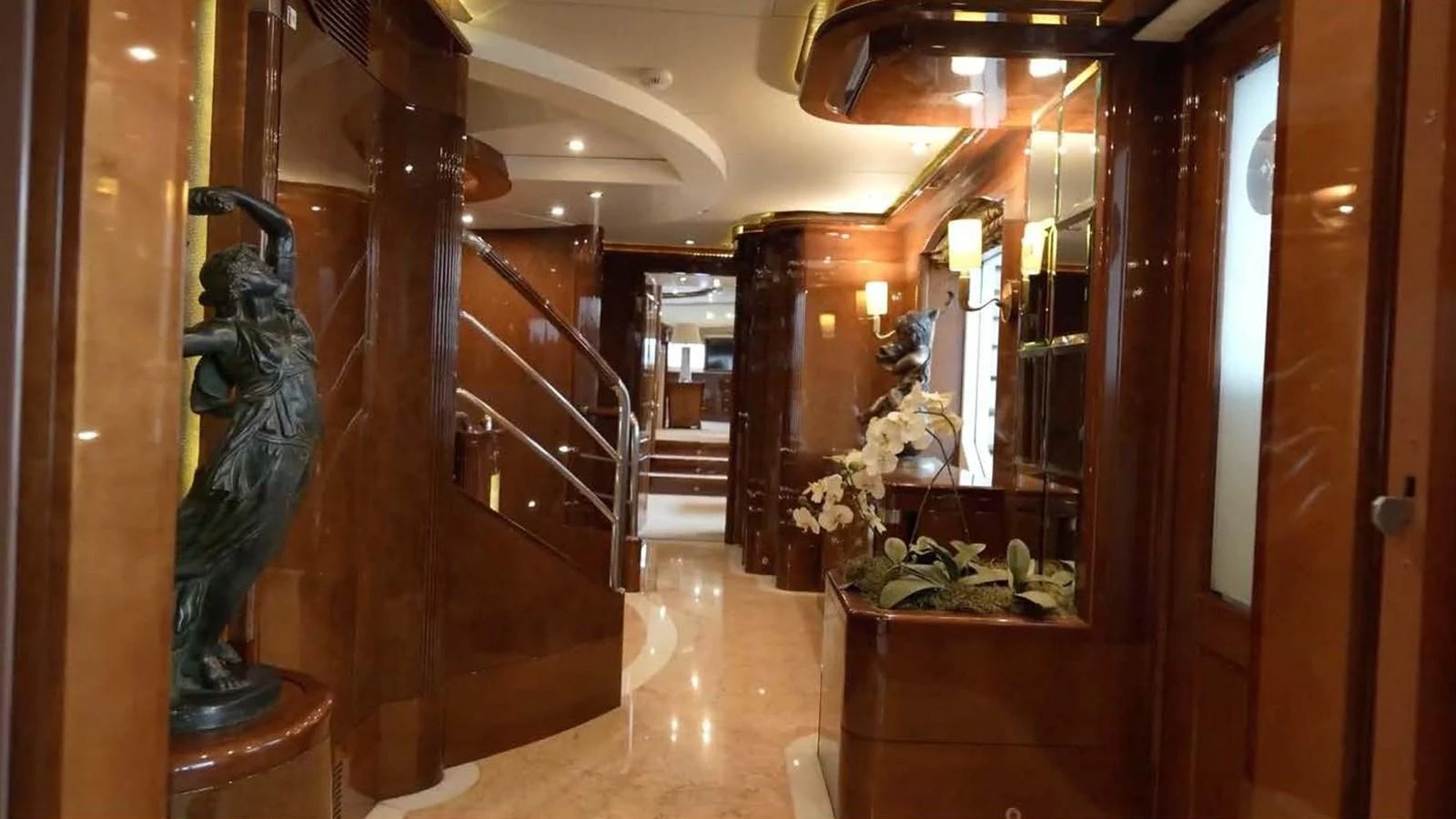 The yacht's interior features a luxurious hallway with elegant wooden finishes and decorative sculptures. aboard DOMANI Yacht for Sale