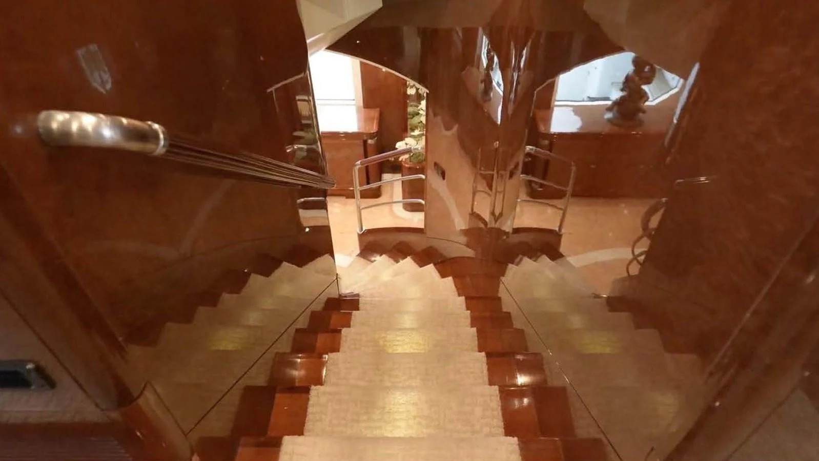 A luxurious wooden staircase descends into the lower deck of the yacht, showcasing elegant design and craftsmanship. aboard DOMANI Yacht for Sale