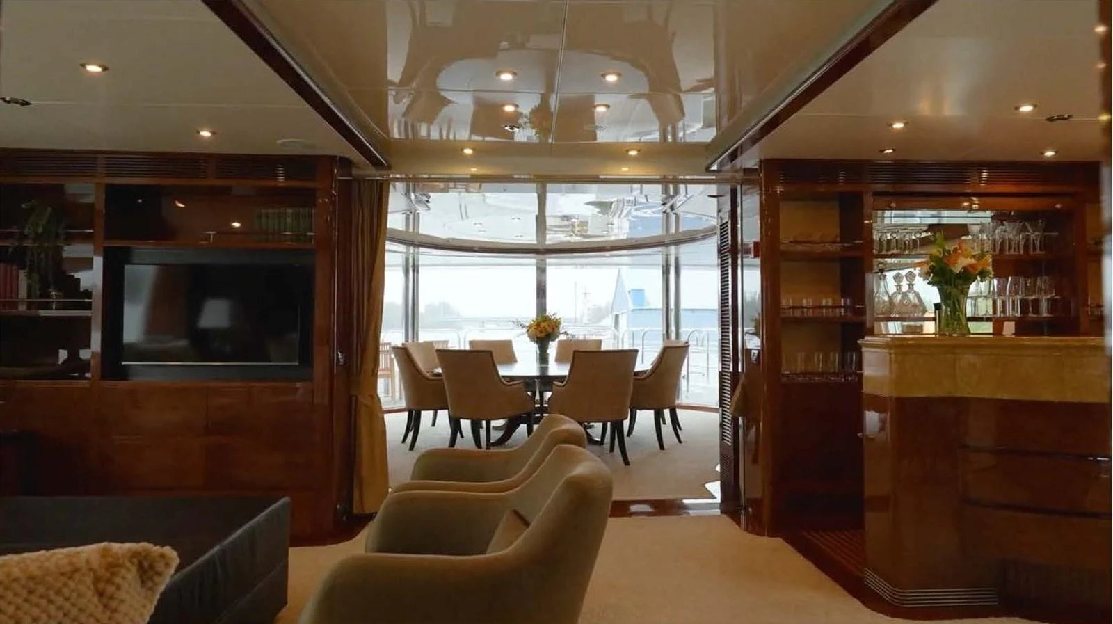 The yacht's salon features elegant seating, a dining area, and a bar with a view of the aft deck. aboard DOMANI Yacht for Sale