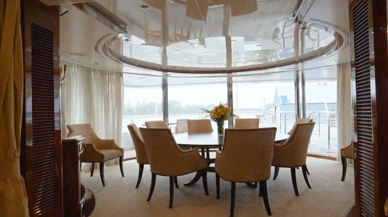 The elegant dining area features a round table surrounded by plush chairs, offering a luxurious setting with panoramic views. aboard DOMANI Yacht for Sale