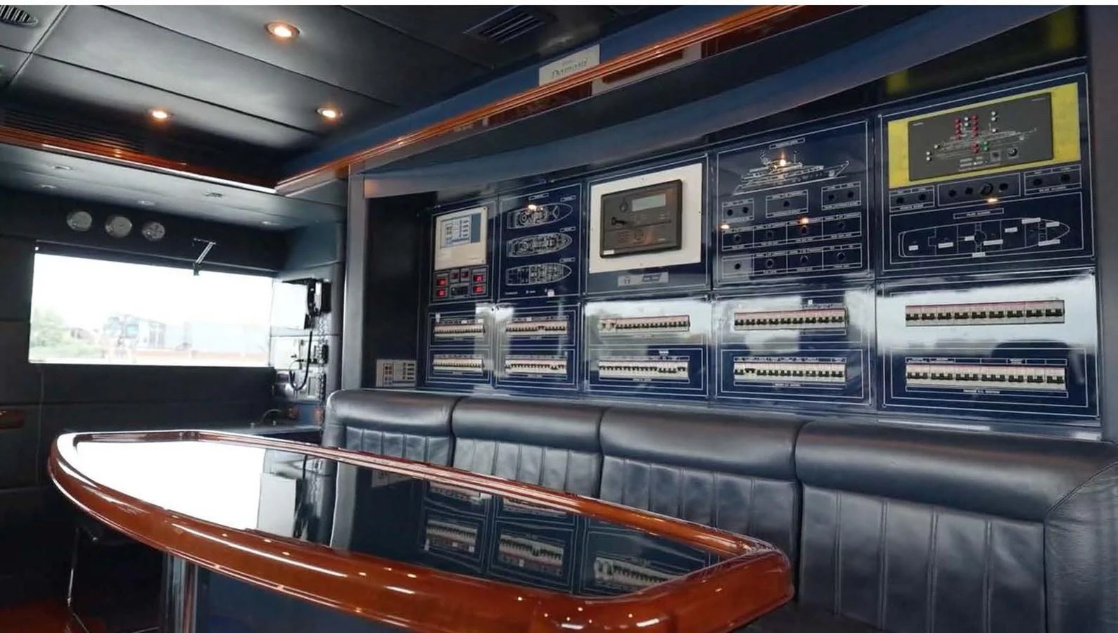The helm station features an array of advanced navigation and control systems, complemented by a sleek, polished table and comfortable seating. aboard DOMANI Yacht for Sale