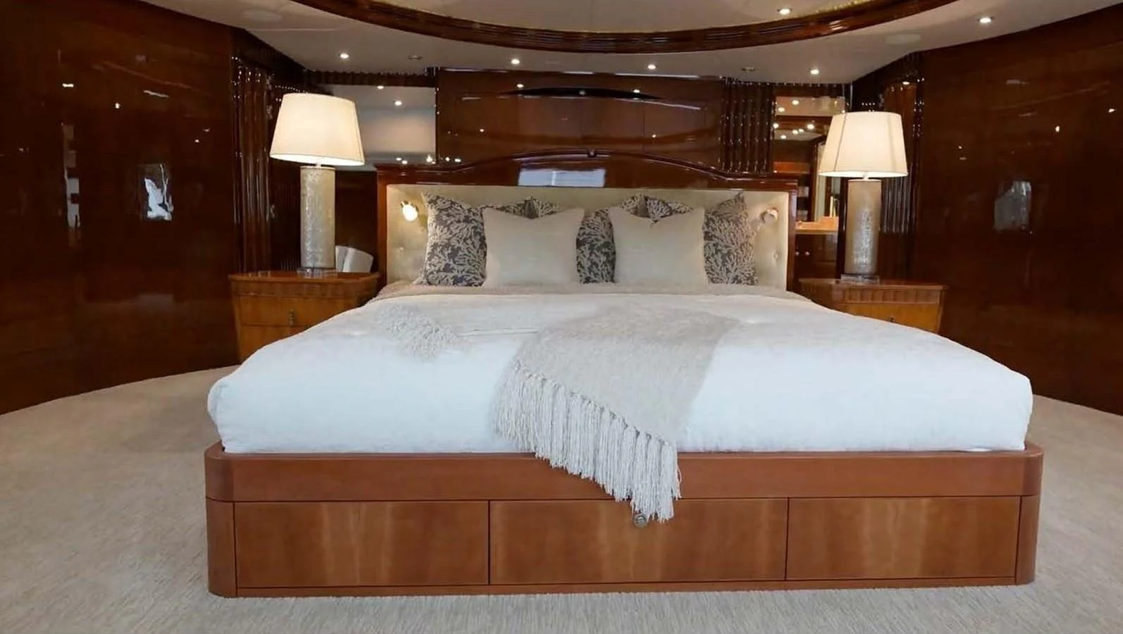 The master stateroom features a luxurious bed with elegant lighting and rich wood finishes. aboard DOMANI Yacht for Sale