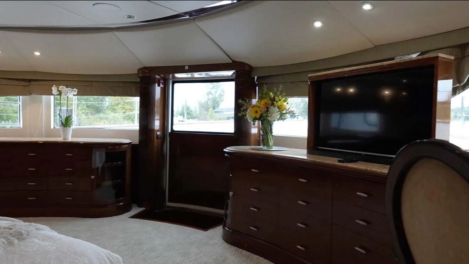 The master stateroom features elegant cabinetry, a large TV, and ample natural light. aboard DOMANI Yacht for Sale