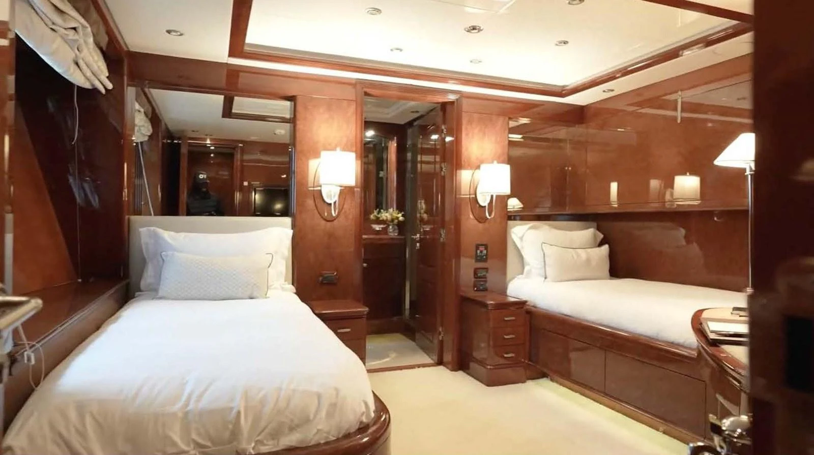 The twin stateroom features two comfortable beds with elegant wood paneling and soft lighting. aboard DOMANI Yacht for Sale