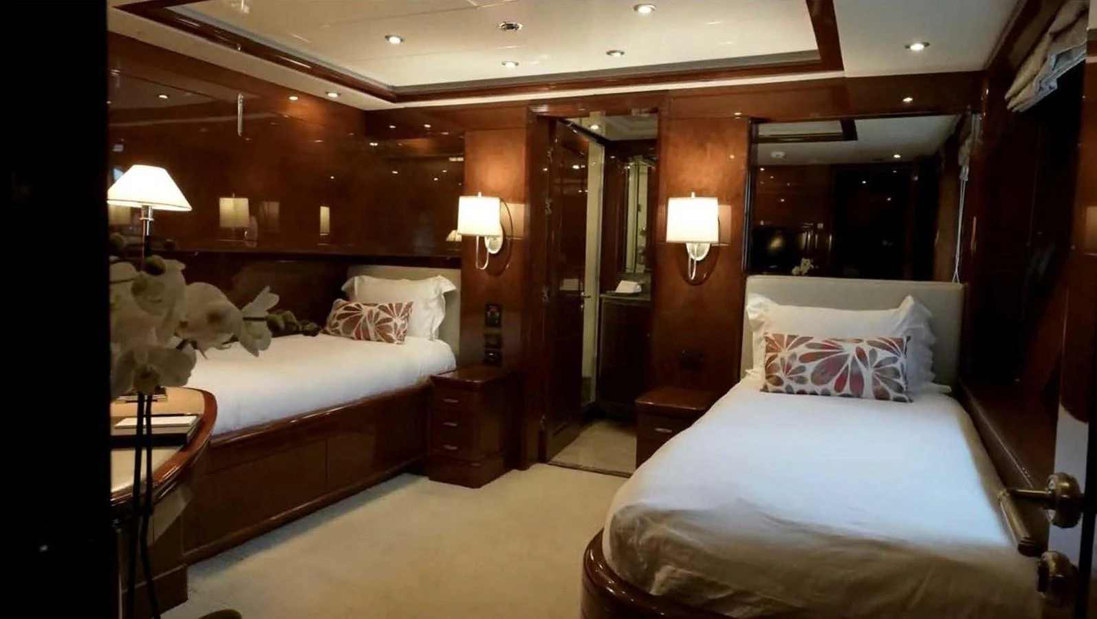 The guest stateroom features two twin beds with elegant wood paneling and soft lighting. aboard DOMANI Yacht for Sale