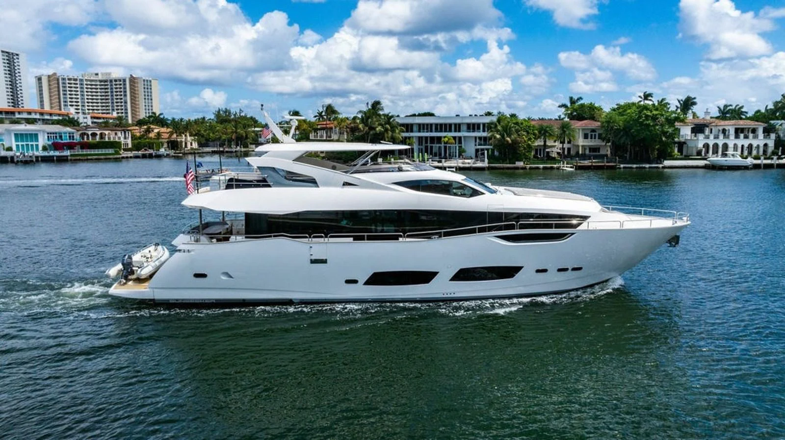 A sleek and modern yacht cruises along a scenic waterfront with luxurious residences in the background. aboard STAR OF THE SEA Yacht for Sale
