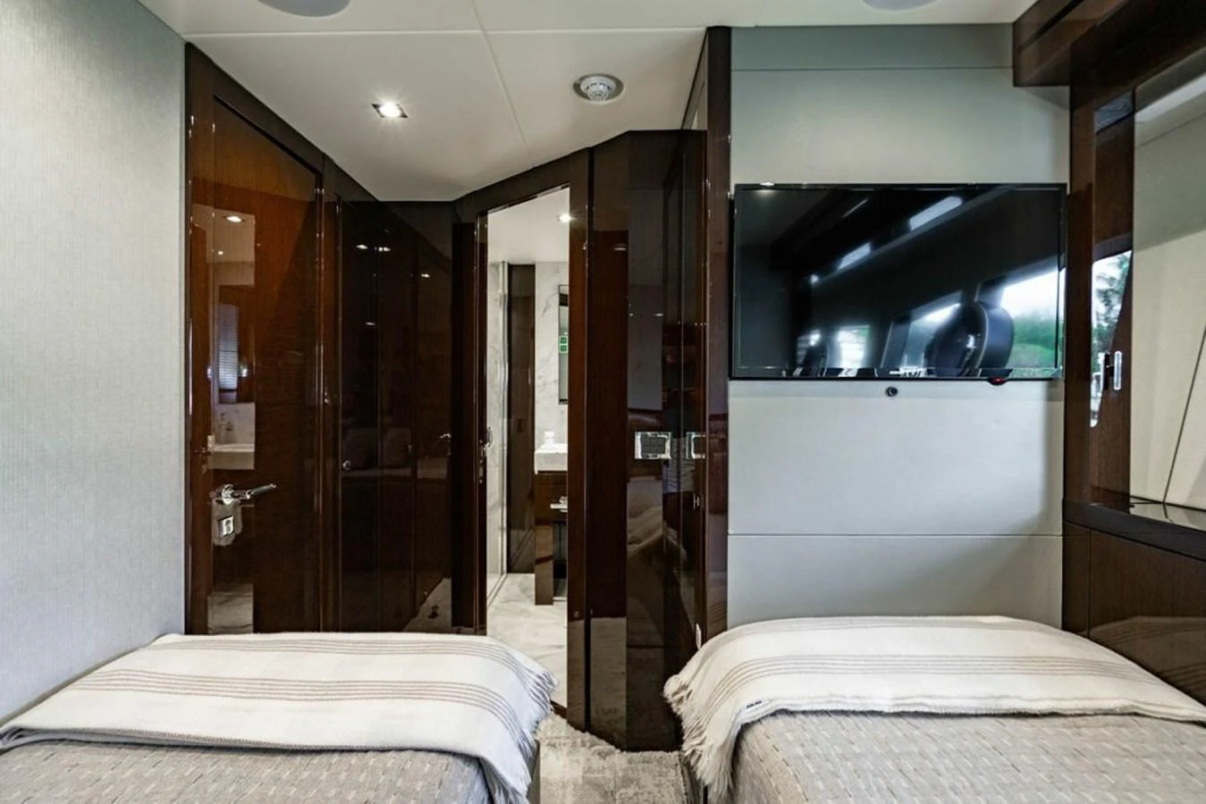 The guest stateroom features twin beds and a sleek modern design with a wall-mounted TV. aboard STAR OF THE SEA Yacht for Sale