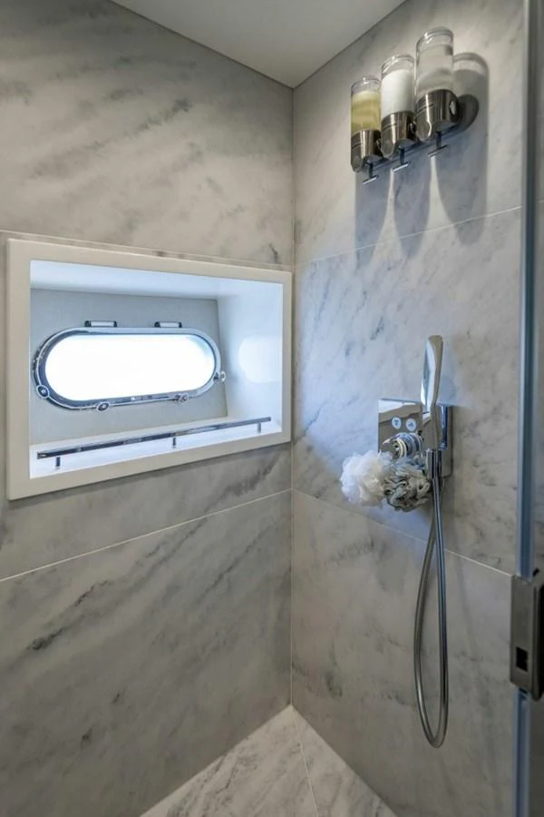 The yacht's bathroom features a sleek, modern design with a marble finish and a porthole window. aboard STAR OF THE SEA Yacht for Sale