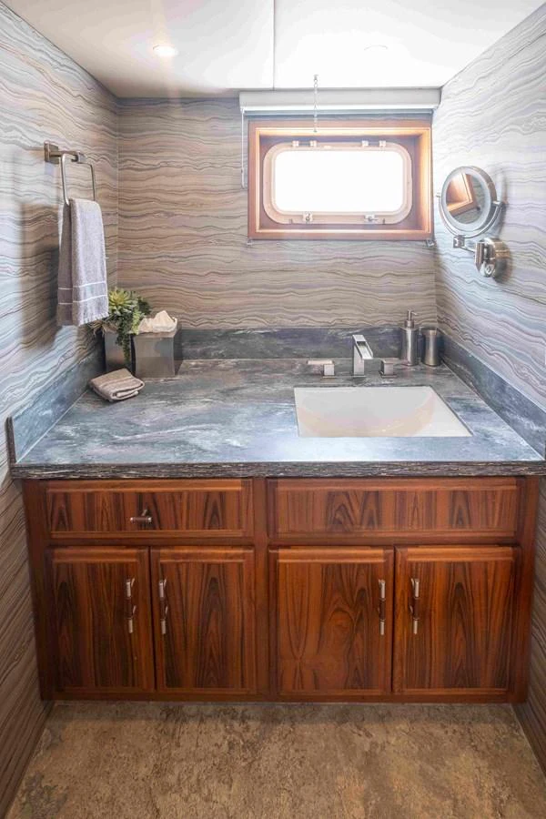 The yacht's bathroom features elegant wood cabinetry and a sleek countertop with modern fixtures. aboard SAPPHIRE SEA II Yacht for Sale