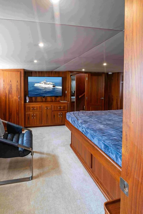 A luxurious stateroom featuring a large bed, wooden cabinetry, and a flat-screen TV displaying a yacht image. aboard SAPPHIRE SEA II Yacht for Sale