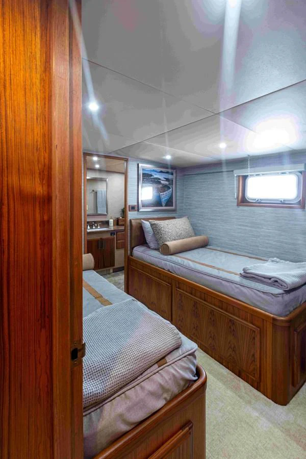 The guest cabin features twin beds with luxurious bedding and warm wooden accents. aboard SAPPHIRE SEA II Yacht for Sale