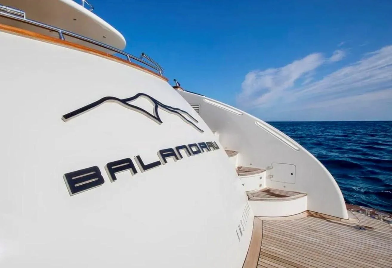 The yacht's name and logo are prominently displayed on the stern against a backdrop of the open sea. aboard BALANDRAU Yacht for Sale