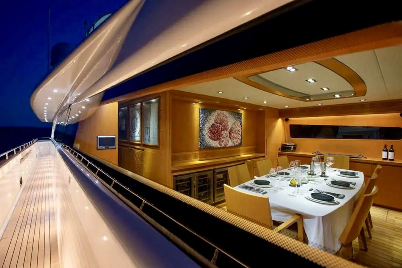 The yacht features a sophisticated dining area with elegant table settings and ambient lighting. aboard BALANDRAU Yacht for Sale