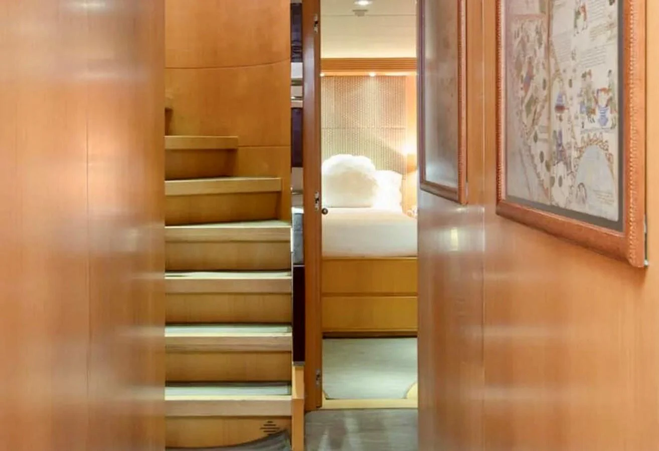 A cozy hallway leads to a well-lit stateroom with wooden finishes. aboard BALANDRAU Yacht for Sale