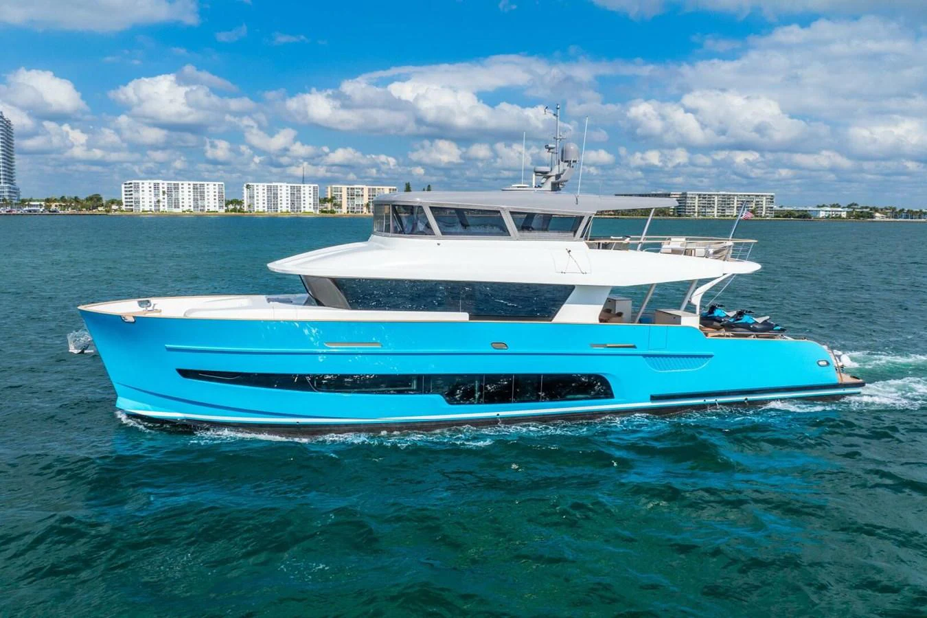 A sleek yacht cruises through the water on a sunny day, showcasing its modern design and vibrant blue hull. aboard LADY SADIE Yacht for Sale