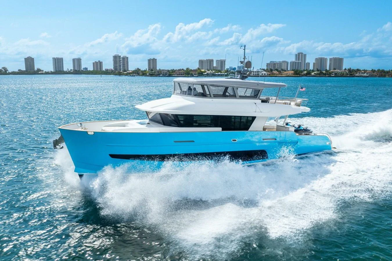 A sleek yacht cruises swiftly through the water, showcasing its modern design against a cityscape backdrop. aboard LADY SADIE Yacht for Sale