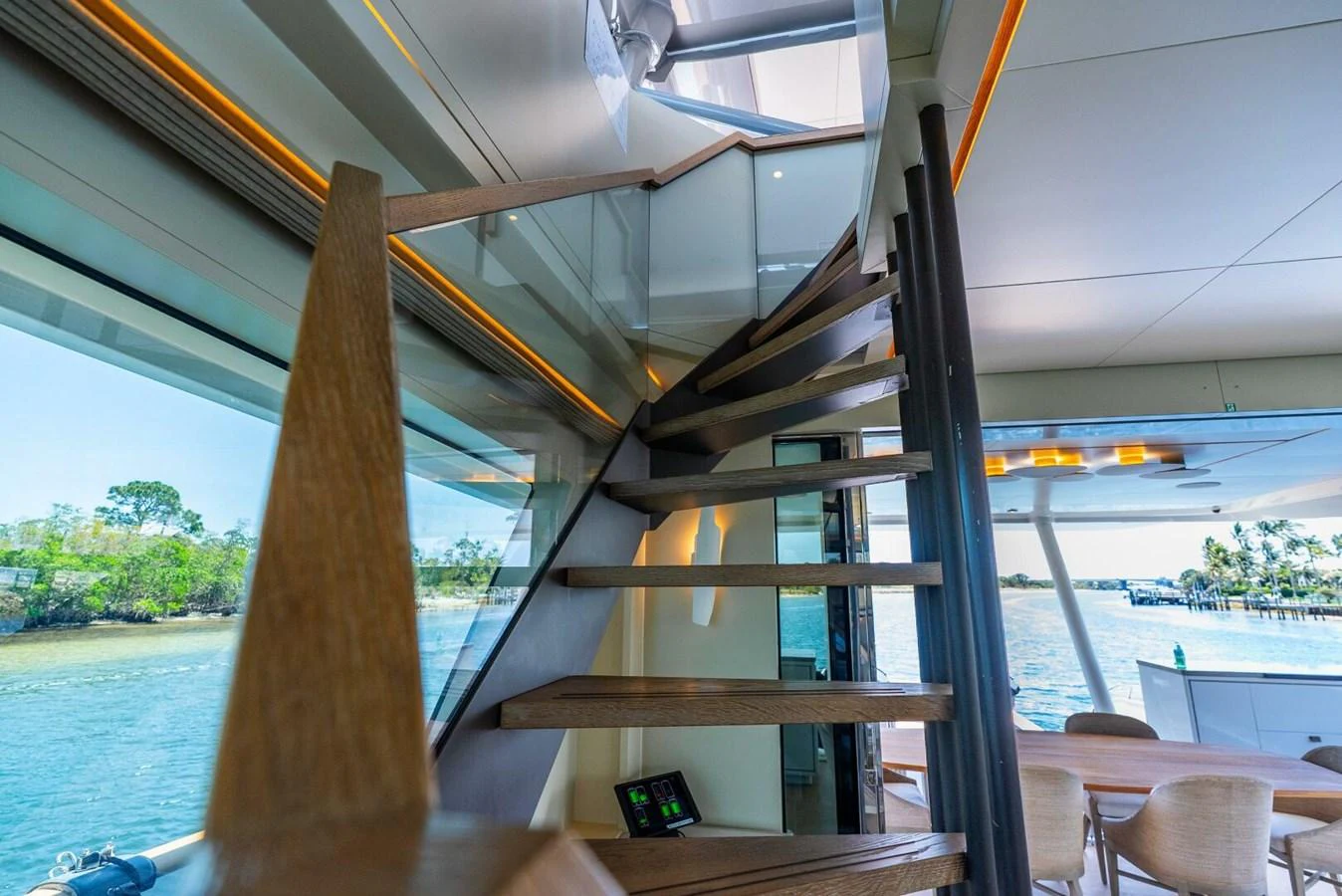 A stylish staircase leads to the upper deck, surrounded by large windows offering scenic views. aboard LADY SADIE Yacht for Sale