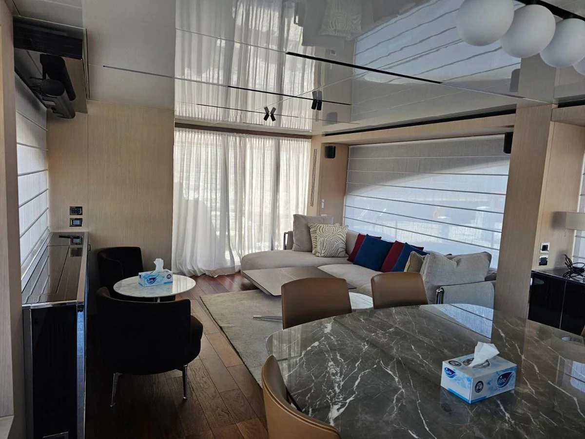 The yacht's interior features a cozy seating area with a modern dining table and ample natural light. aboard YAS 88 Yacht for Sale