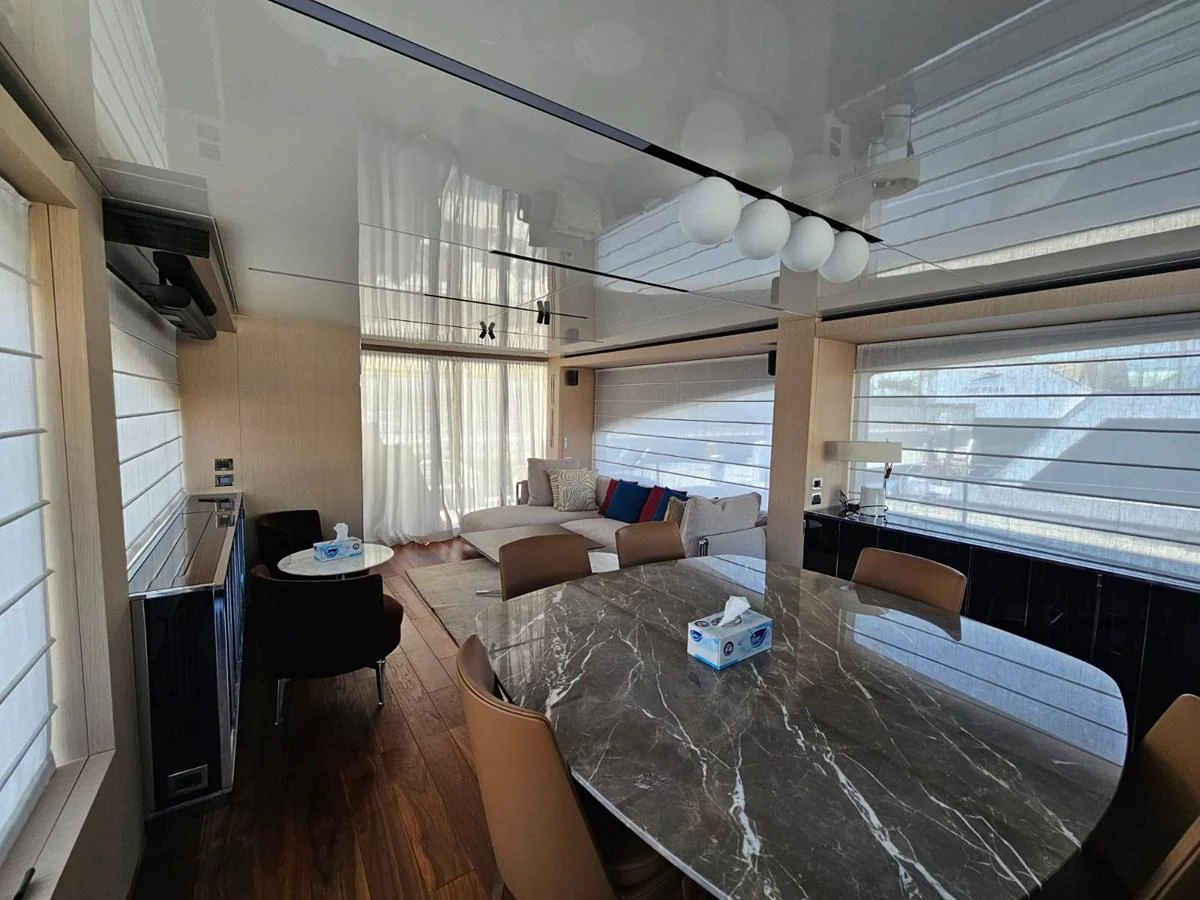 The yacht's salon features a spacious seating area and a dining table with elegant finishes. aboard YAS 88 Yacht for Sale