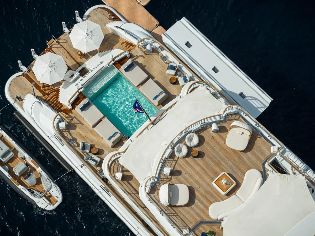 The sundeck features a luxurious pool area with ample lounging spaces and elegant umbrellas. aboard SYNTHESIS Yacht for Sale