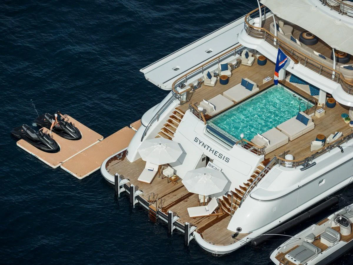 The yacht's aft deck features a luxurious pool and lounging area with direct access to the water. aboard SYNTHESIS Yacht for Sale