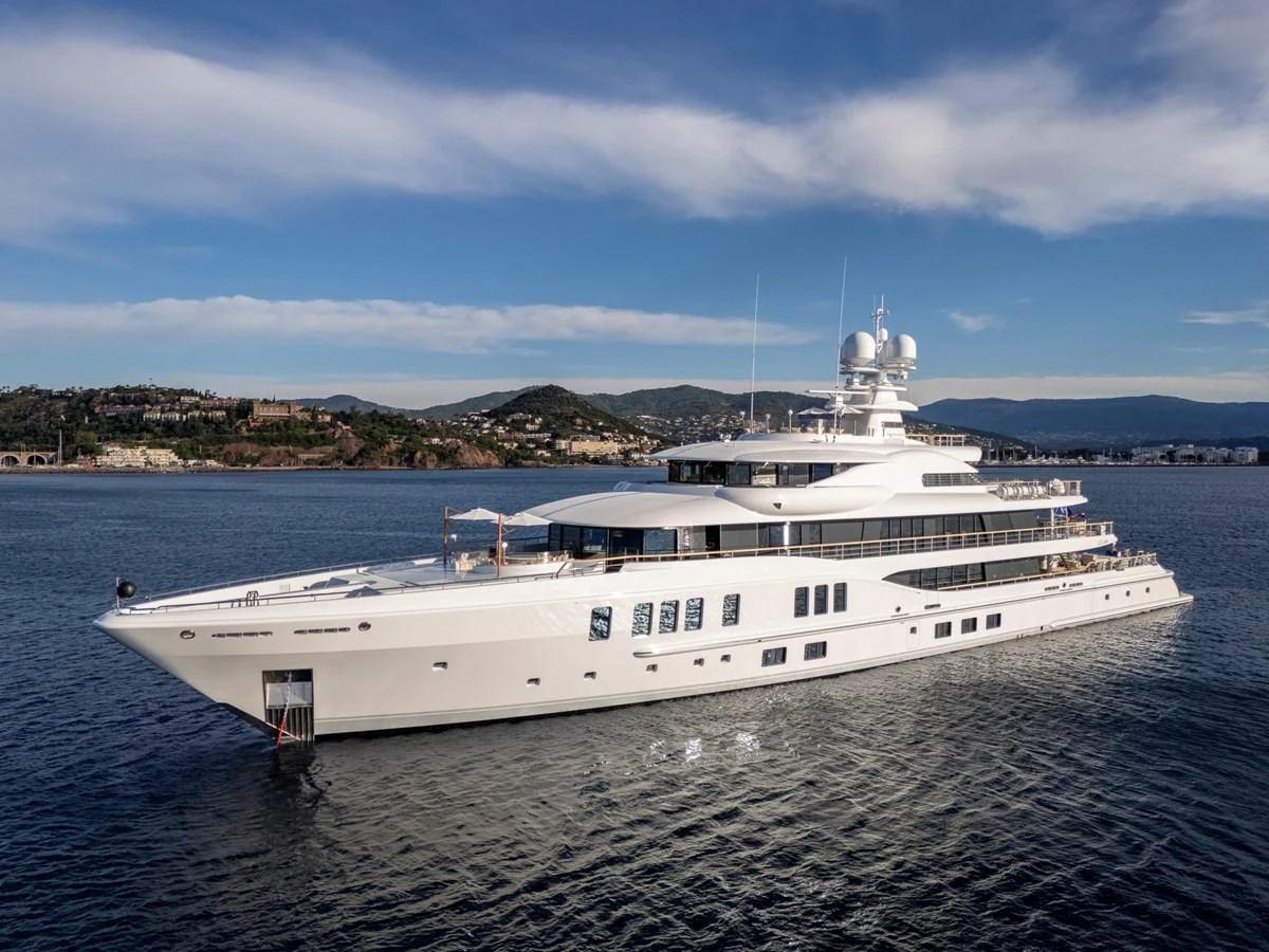 A luxurious yacht glides gracefully on calm waters with a scenic coastal backdrop. aboard SYNTHESIS Yacht for Sale