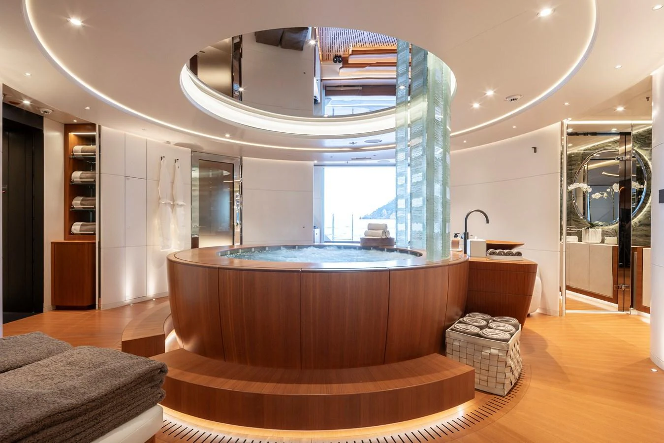 The yacht features a luxurious spa area with a large circular hot tub and elegant wood finishes. aboard SYNTHESIS Yacht for Sale