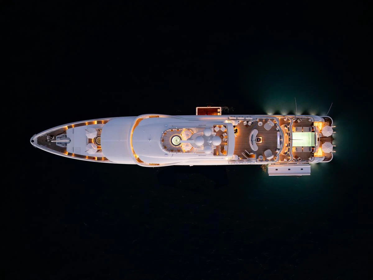 An aerial view of a beautifully illuminated yacht at night, showcasing its elegant design and luxurious amenities. aboard SYNTHESIS Yacht for Sale