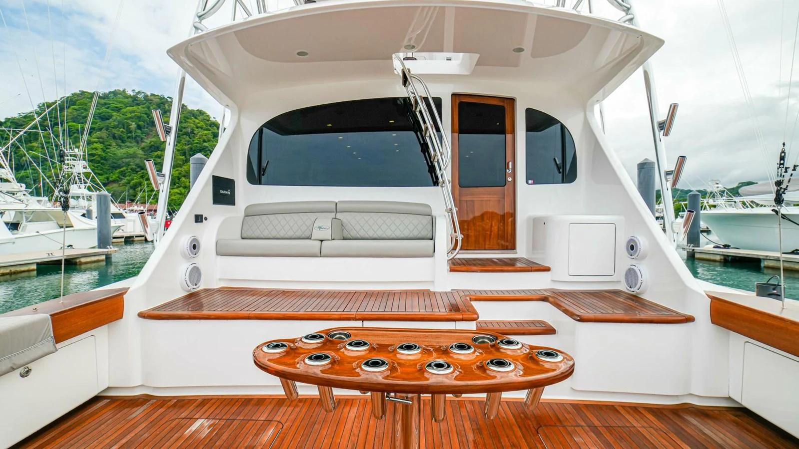 The aft deck features a spacious seating area with a polished wooden floor and a central table designed for fishing gear. aboard FREE SPOOL Yacht for Sale