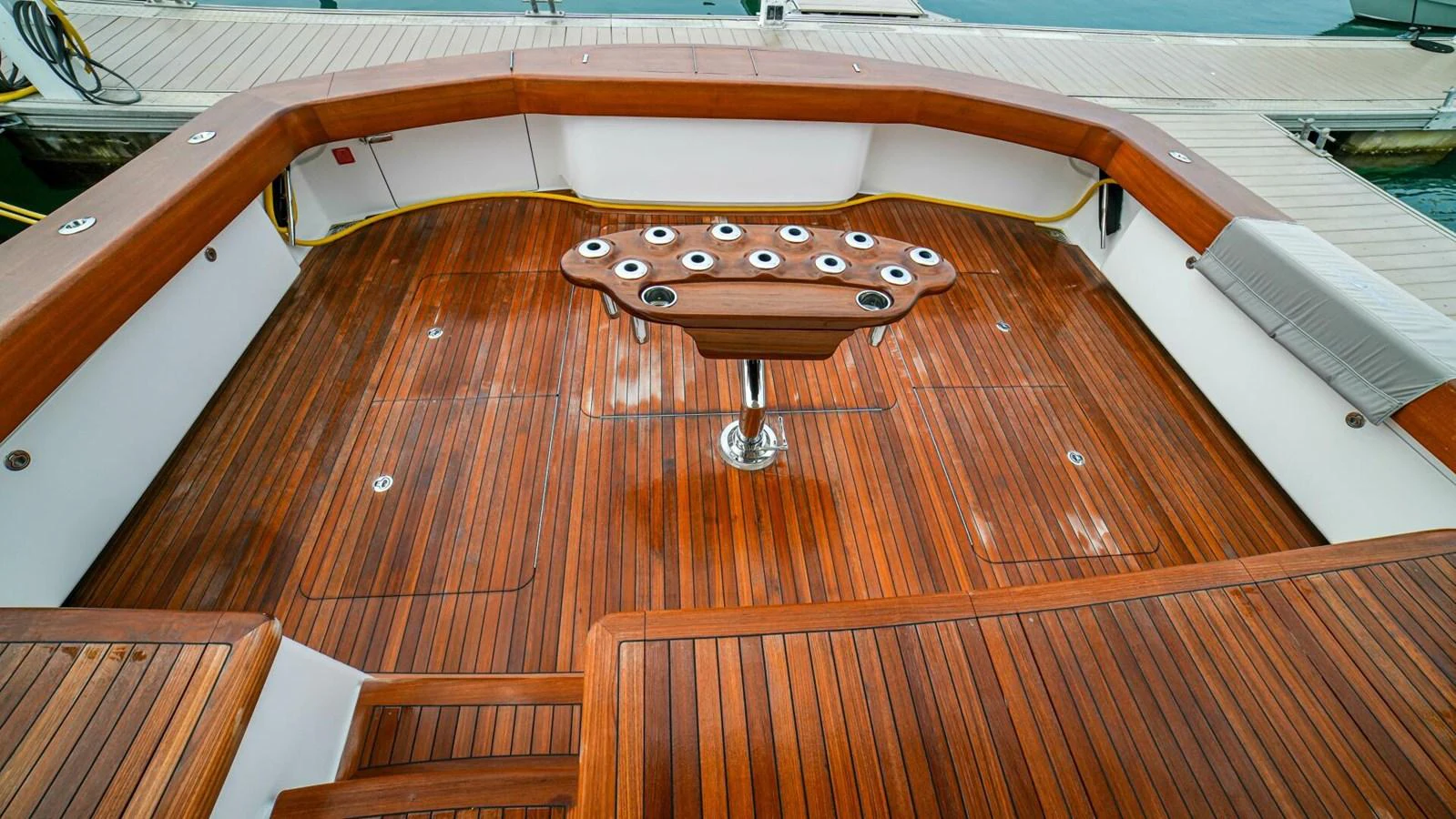The aft deck features a beautifully crafted wooden floor with a central table designed for fishing rod holders. aboard FREE SPOOL Yacht for Sale