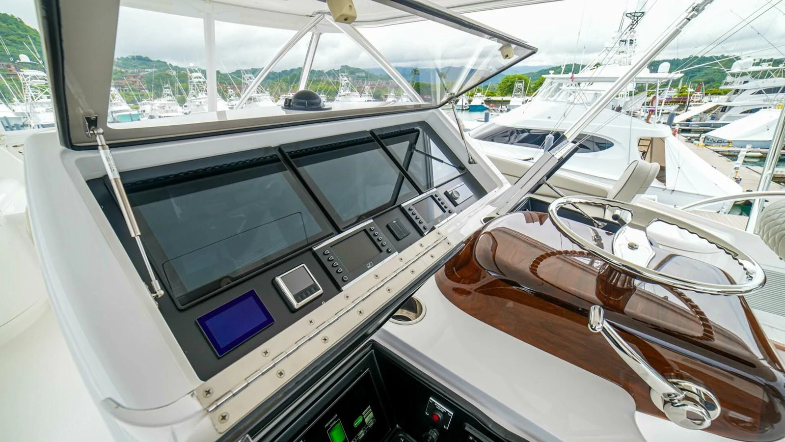 The helm station features advanced navigation equipment and a polished wooden steering wheel. aboard FREE SPOOL Yacht for Sale