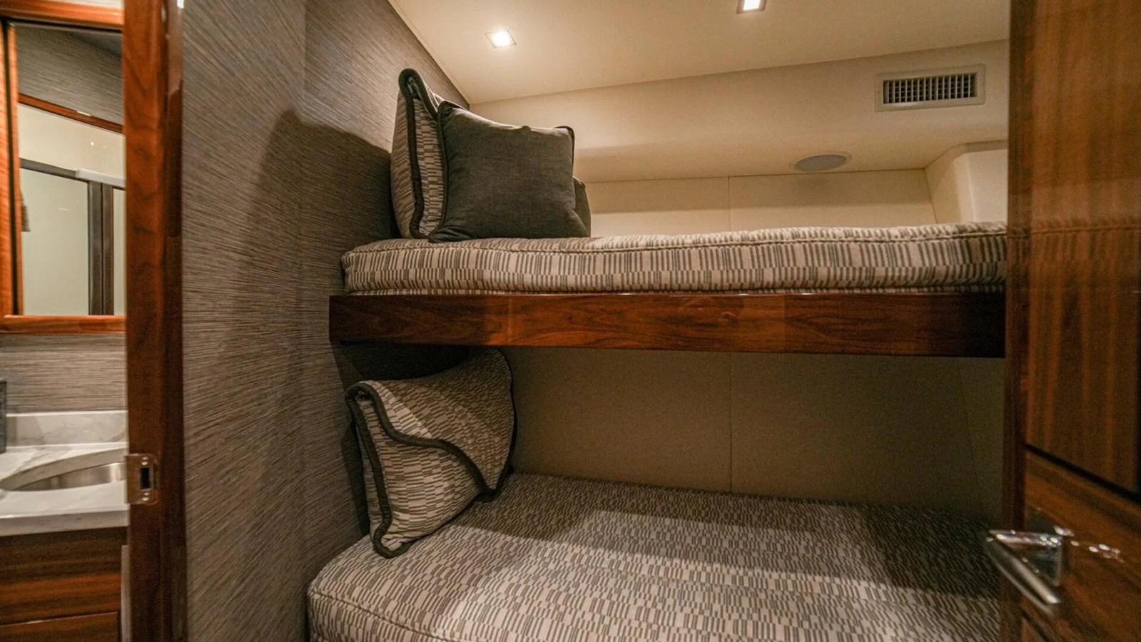 The guest cabin features cozy bunk beds with elegant bedding and warm lighting. aboard FREE SPOOL Yacht for Sale