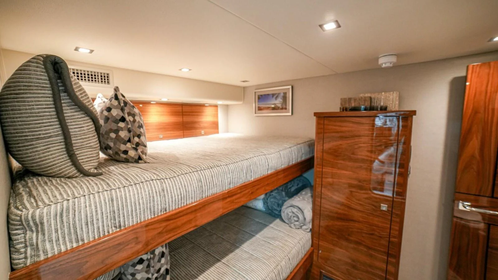 The guest cabin features cozy bunk beds with elegant wood finishes and soft lighting. aboard FREE SPOOL Yacht for Sale