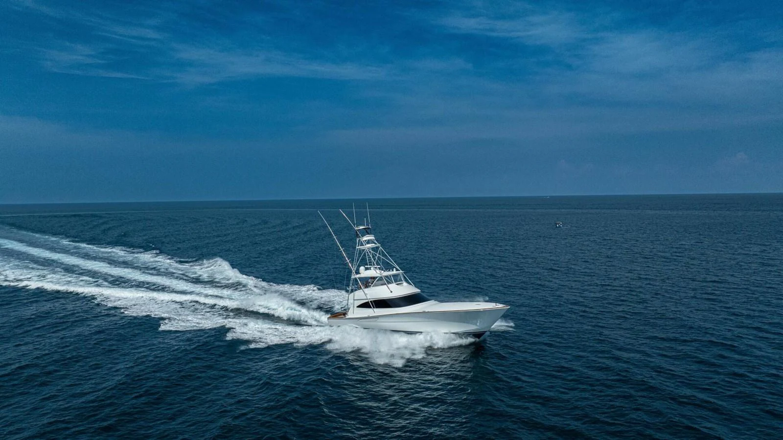 A sleek yacht cruises swiftly across the open sea under a clear blue sky. aboard FREE SPOOL Yacht for Sale