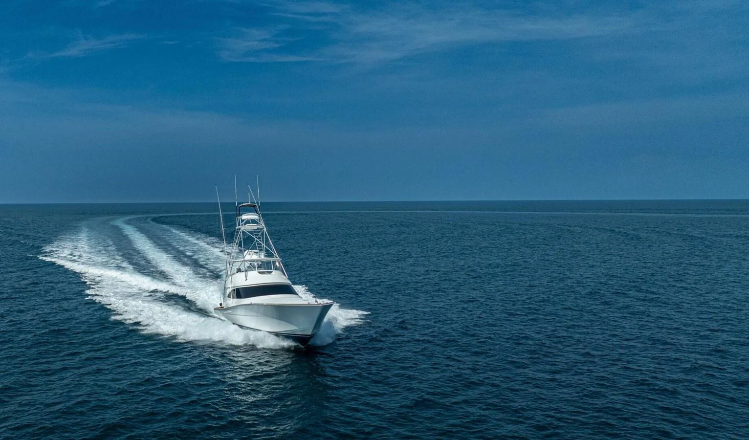 A sleek yacht cruises swiftly across open waters under a clear blue sky. aboard FREE SPOOL Yacht for Sale