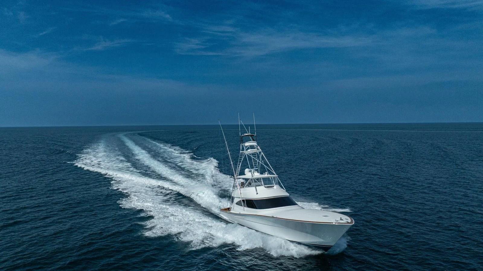A sleek yacht cruises swiftly through open waters under a clear blue sky. aboard FREE SPOOL Yacht for Sale