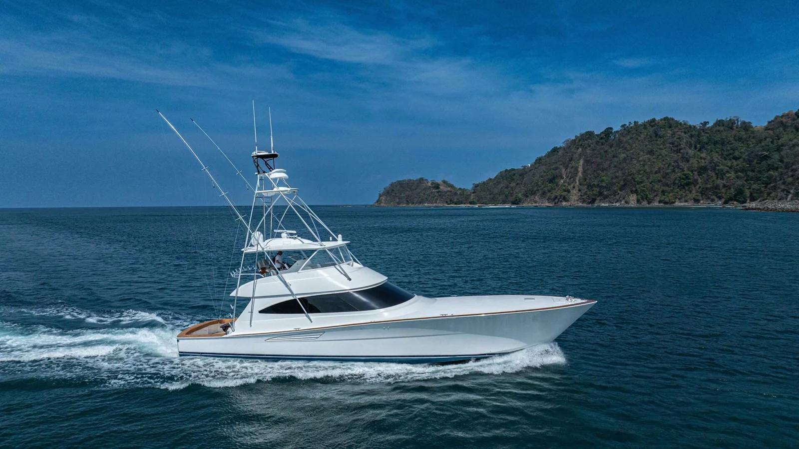 A sleek yacht cruises through calm waters with a scenic backdrop. aboard FREE SPOOL Yacht for Sale