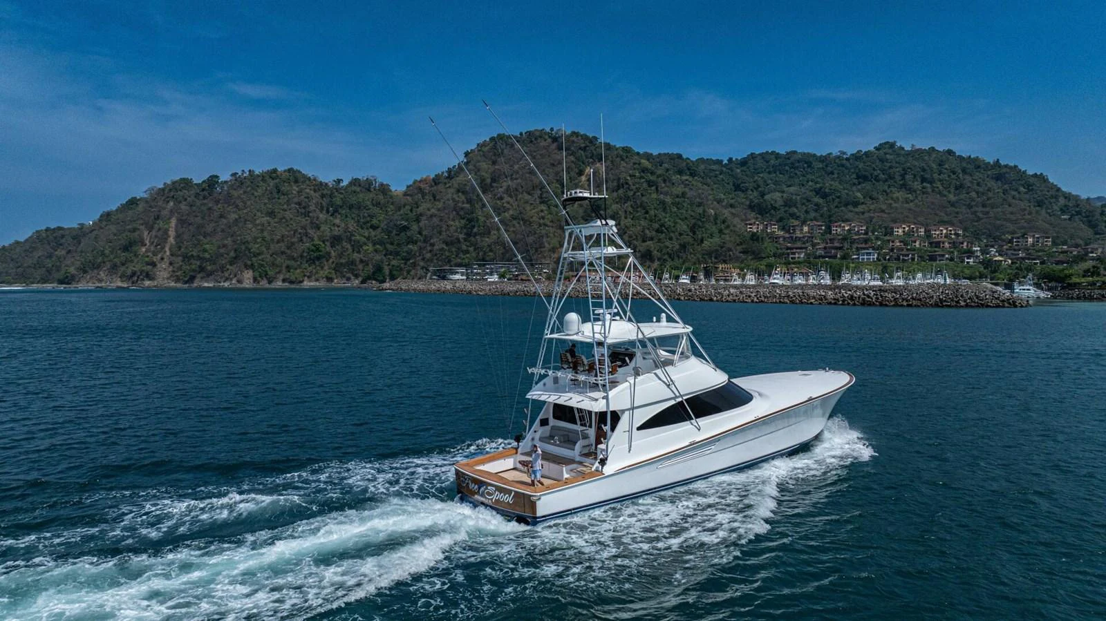 A sleek yacht cruises through calm waters near a scenic coastline. aboard FREE SPOOL Yacht for Sale