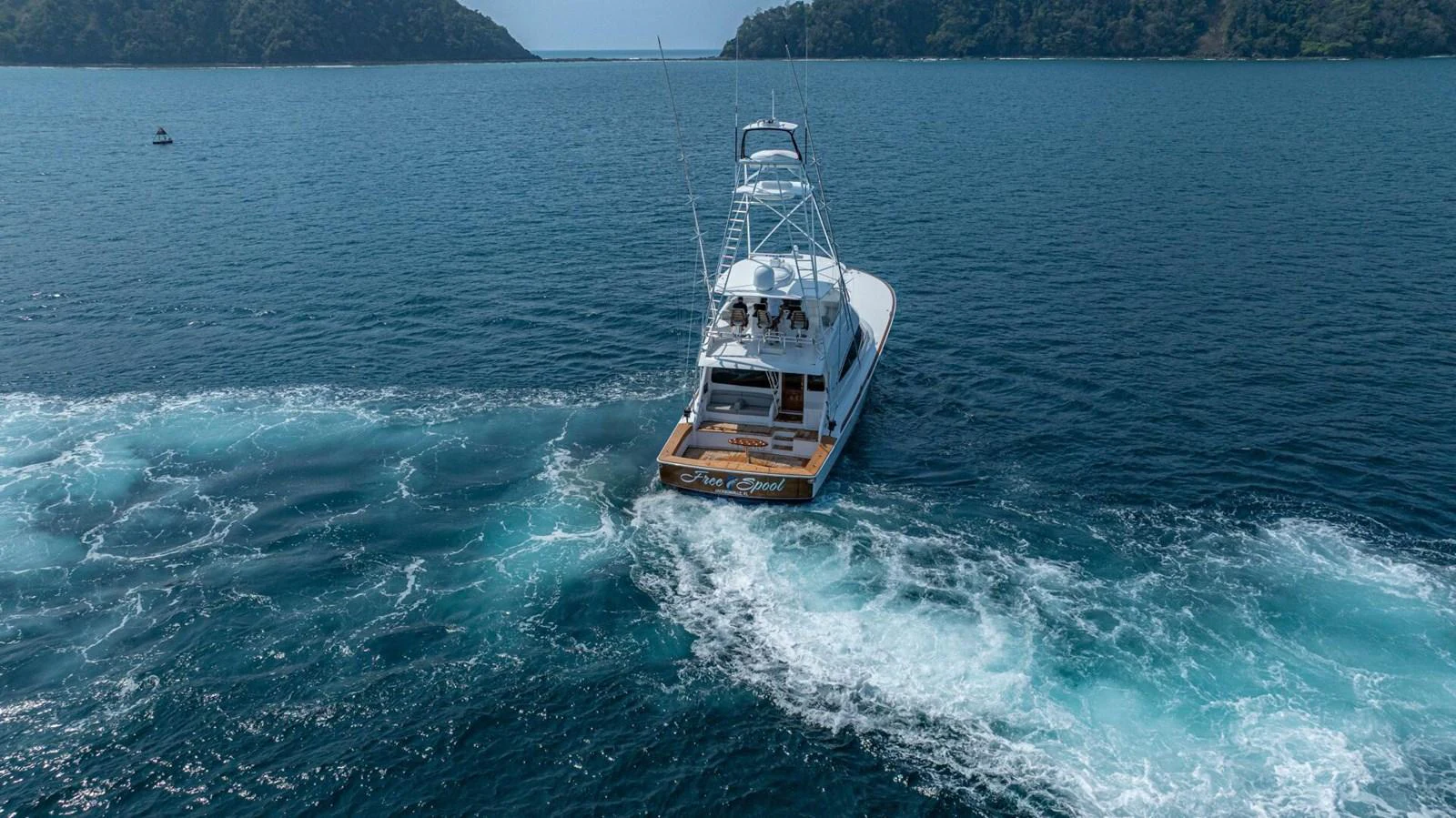 A yacht cruises through serene blue waters surrounded by lush islands. aboard FREE SPOOL Yacht for Sale