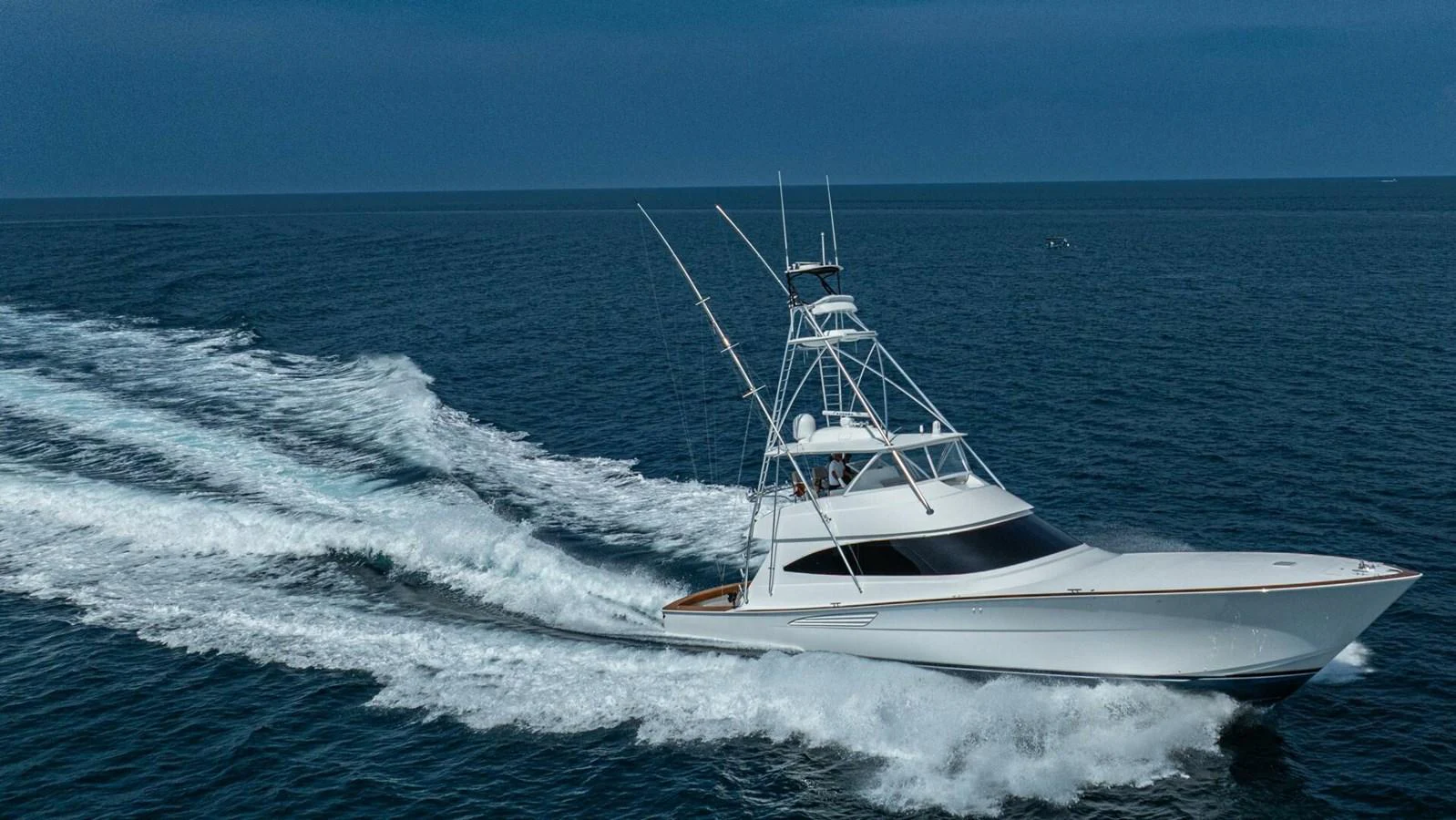 A sleek yacht cruises swiftly through the open sea under a clear sky. aboard FREE SPOOL Yacht for Sale