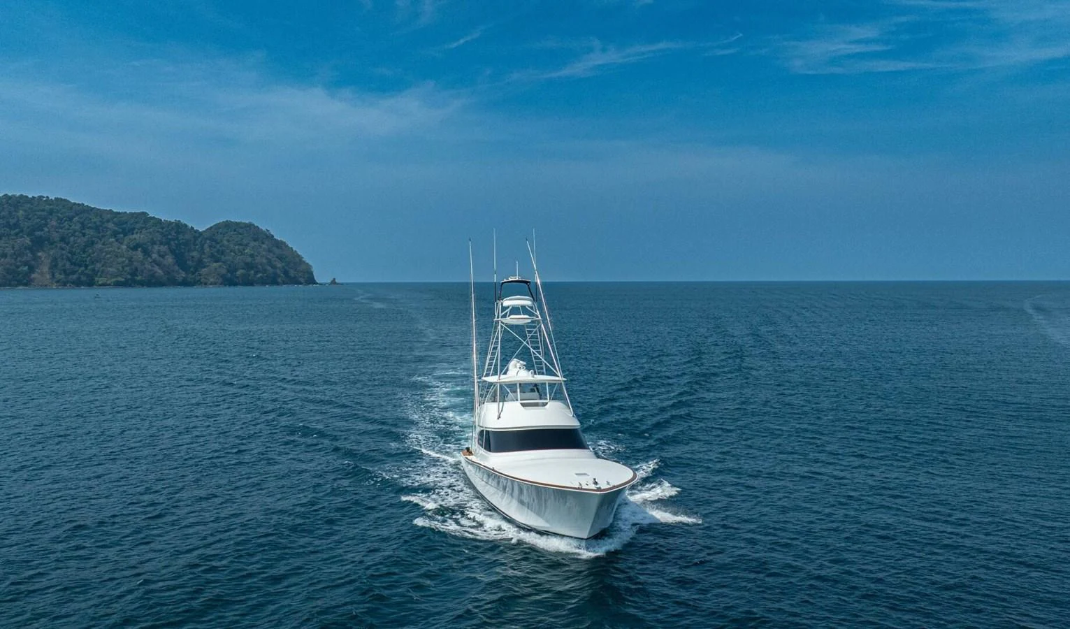A sleek yacht cruises through calm blue waters under a clear sky. aboard FREE SPOOL Yacht for Sale