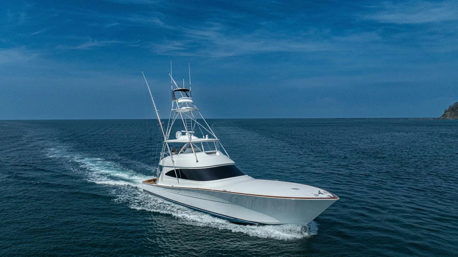 A sleek yacht cruises through calm waters under a clear blue sky. aboard FREE SPOOL Yacht for Sale