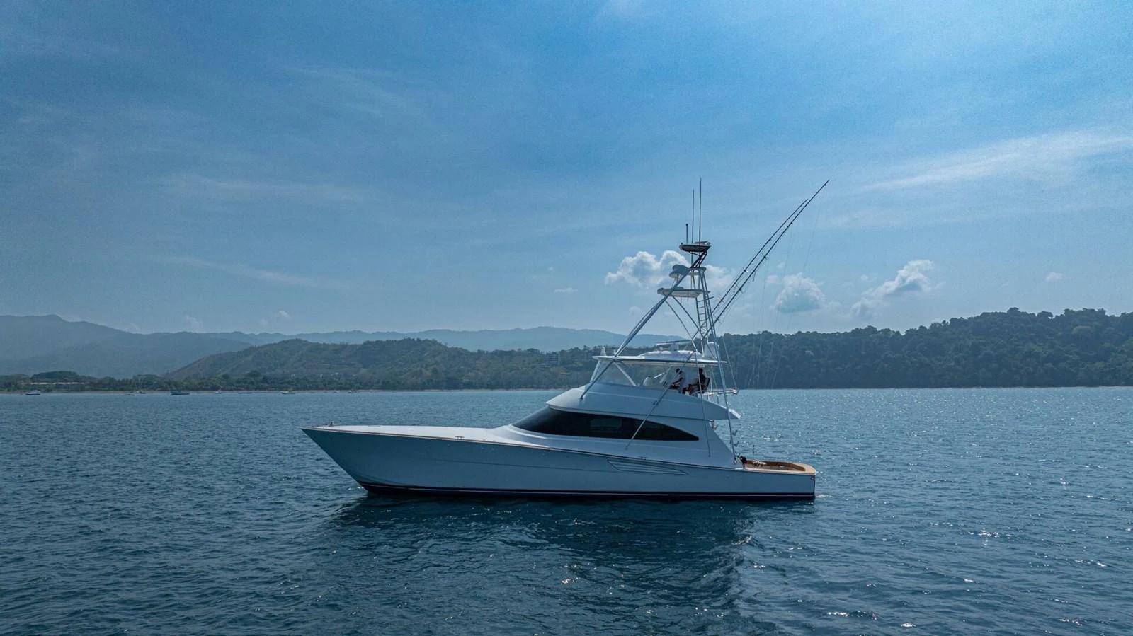A sleek yacht glides gracefully on calm waters under a clear blue sky. aboard FREE SPOOL Yacht for Sale