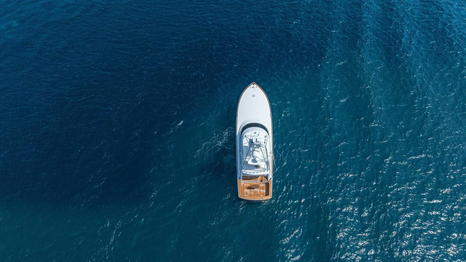 An aerial view of a sleek yacht cruising through deep blue waters. aboard FREE SPOOL Yacht for Sale