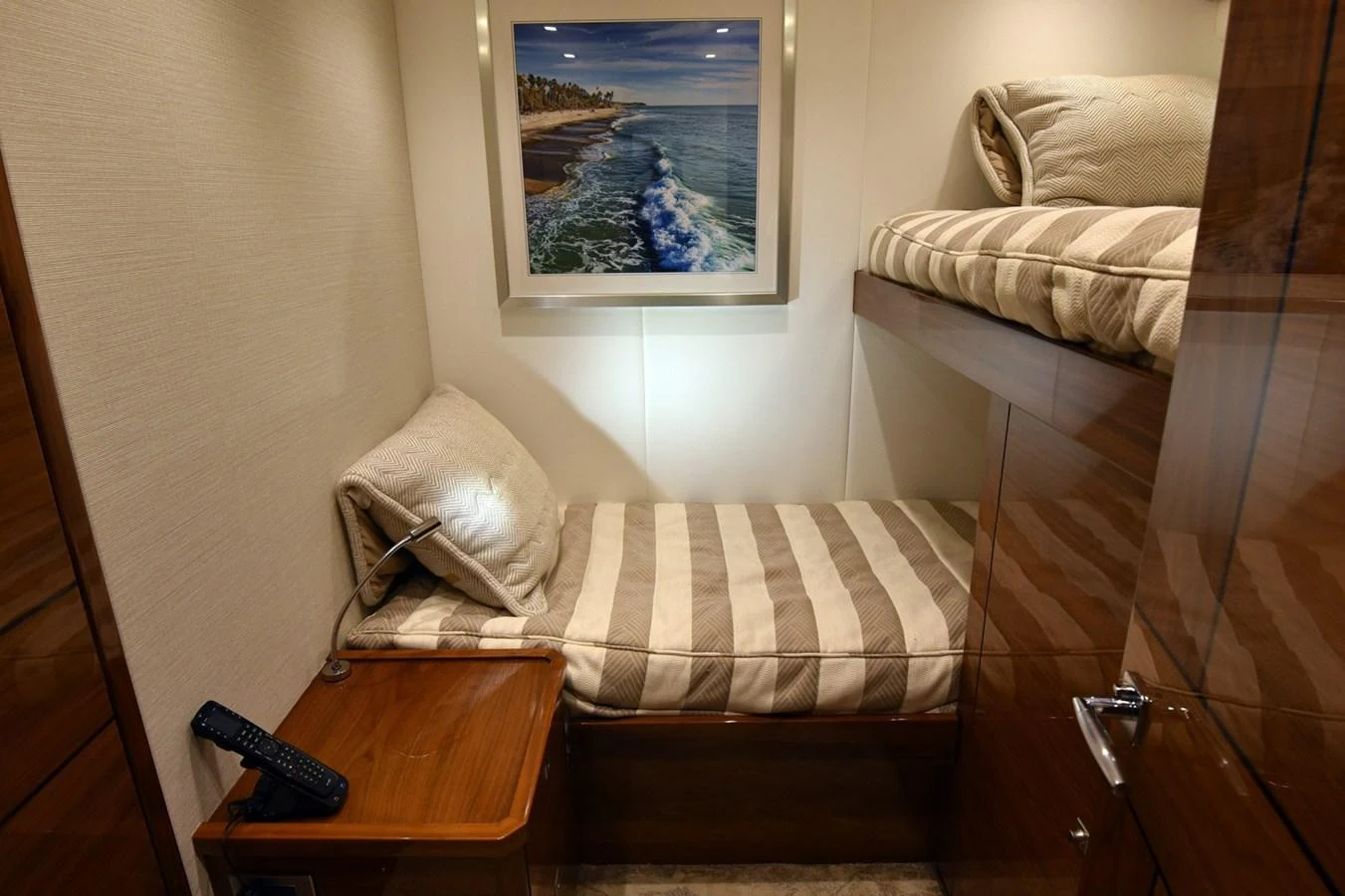 A cozy guest cabin featuring twin bunk beds and a framed seascape painting. aboard PRIMETIME Yacht for Sale