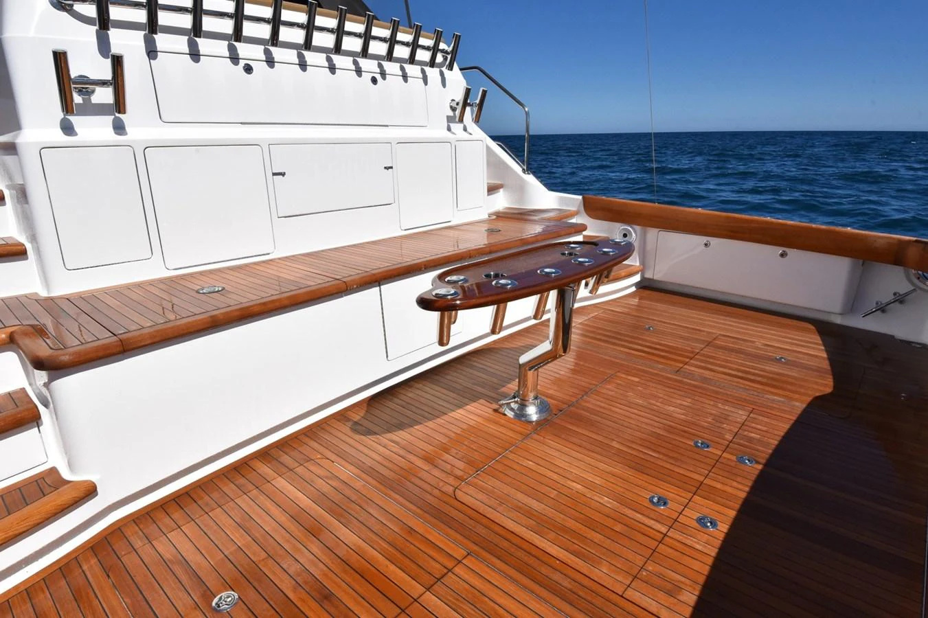 The aft deck features a spacious teak flooring with a mounted table and ample storage compartments. aboard PRIMETIME Yacht for Sale