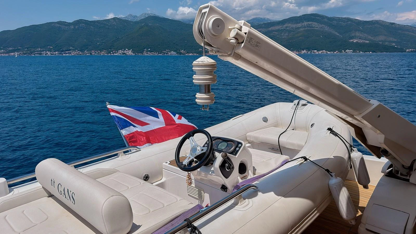 A sleek tender with comfortable seating and a steering console, set against a stunning coastal backdrop. aboard GANS Yacht for Sale