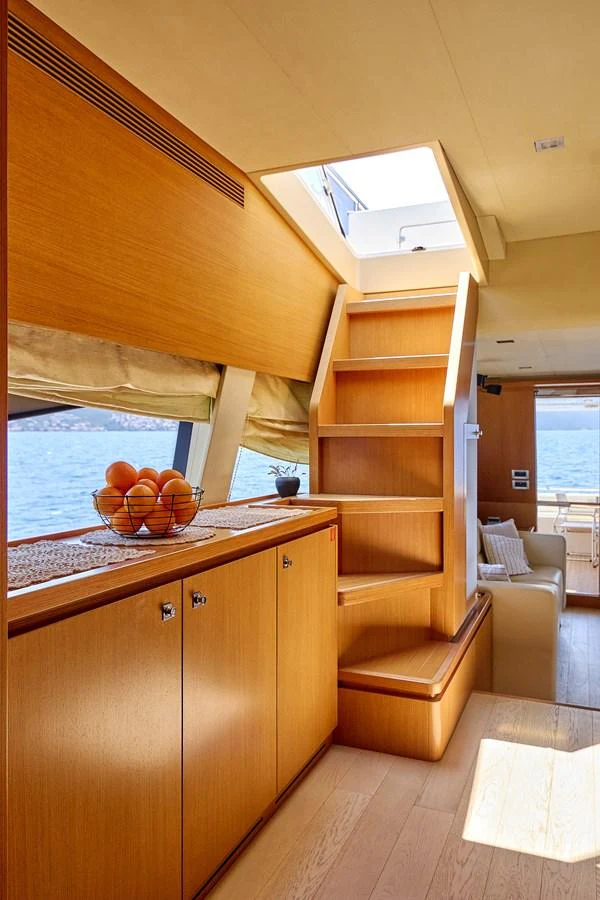 The yacht's interior features a staircase leading to an upper deck, with a bowl of oranges adding a touch of freshness. aboard GANS Yacht for Sale